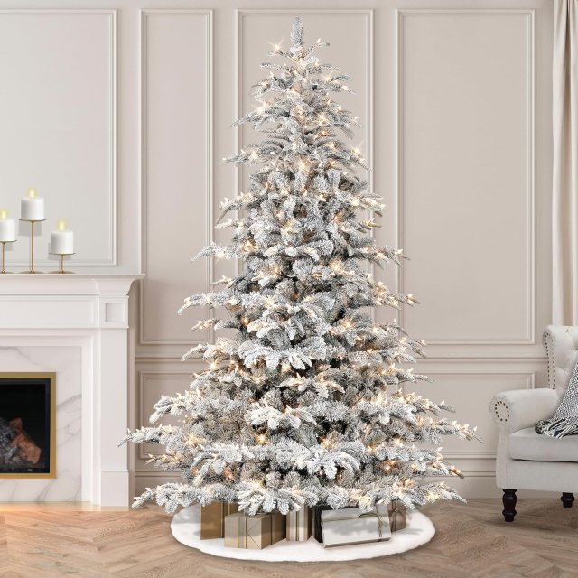 Puleo International pre-lit flocked Aspen Fir artificial Christmas tree with 700 clear lights displayed in an elegant living room.
