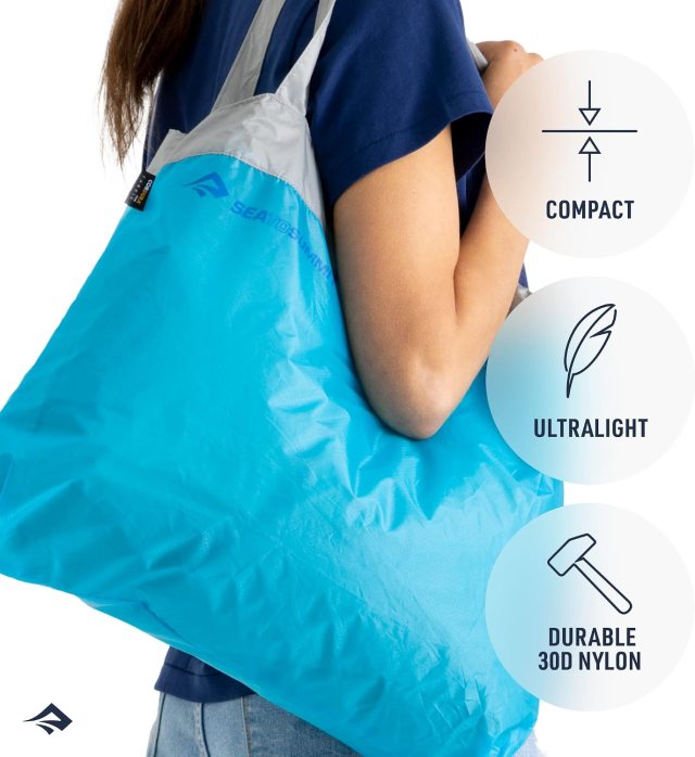 Sea to Summit Ultra-Sil reusable shopping bag in Atoll Blue carried over a woman's shoulder, showing its roomy 30-liter capacity.